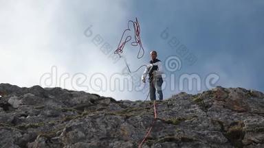 登山者<strong>站在山顶</strong>时，动作缓慢，抛出一根绳子.